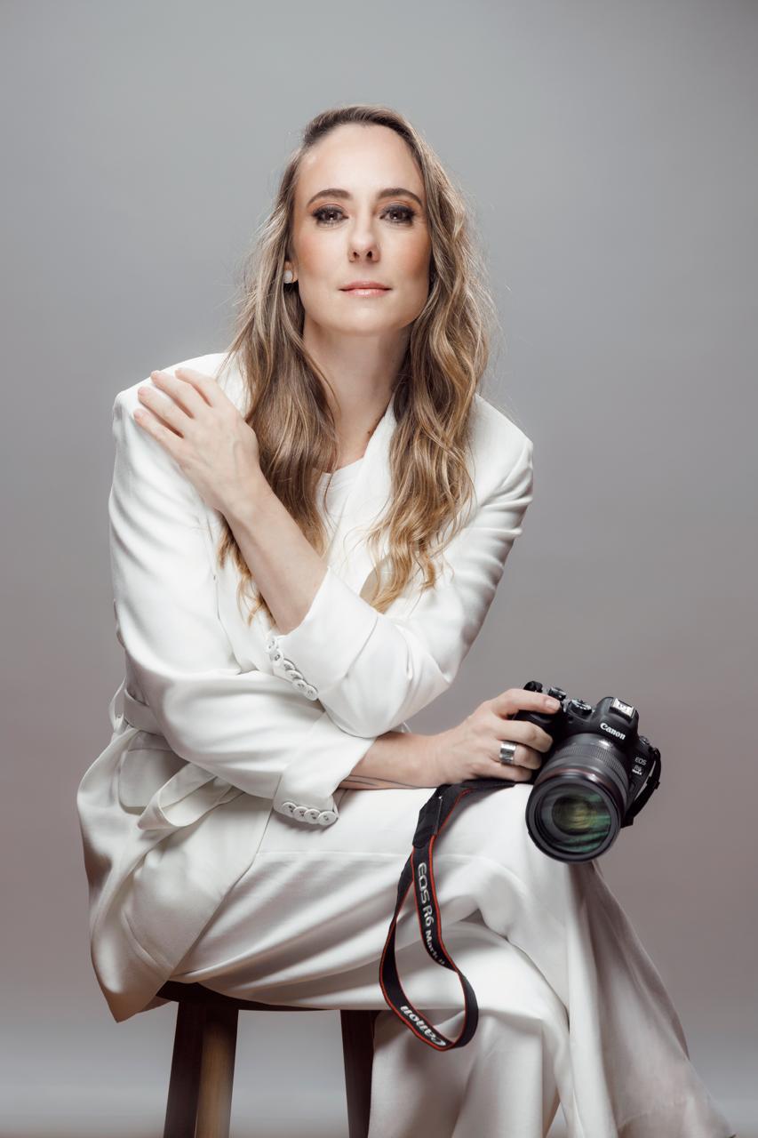 Retrato de Mari Siqueira sentada com sua câmera Canon