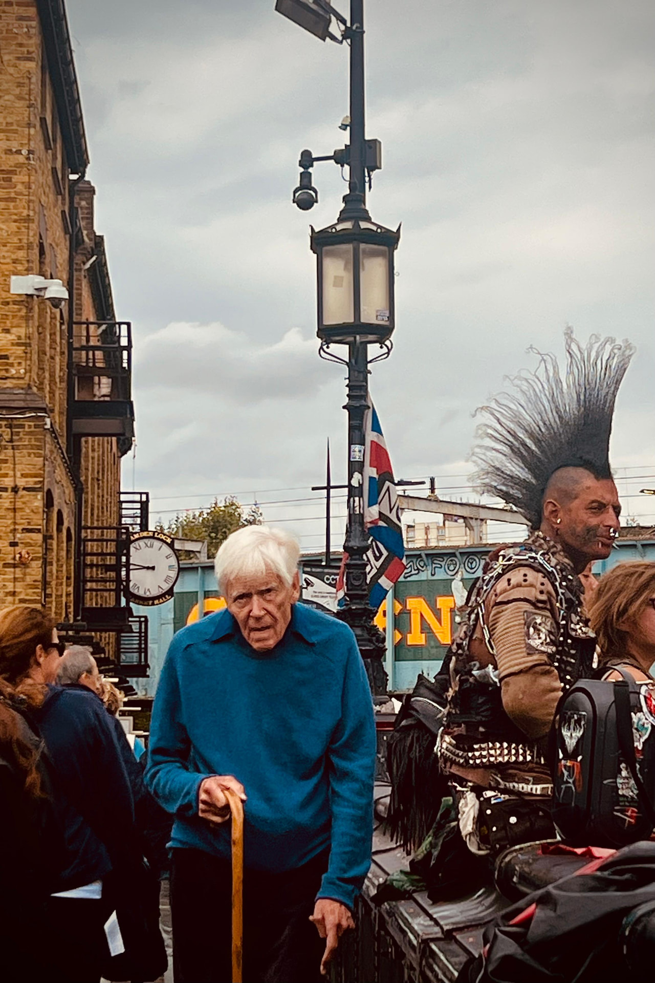 Senhor de bengala e punk de moicano dividindo a mesma calçada em Camden Town, Londres
